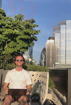 picture of Liam Hartley on top of the Schroders office with his laptop in central London